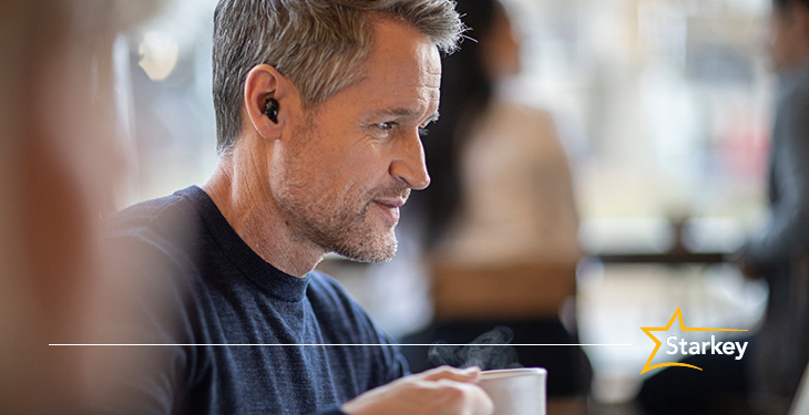 Man wearing the Starkey Livio Edge AI Custom Hearing Aids in a coffee shop