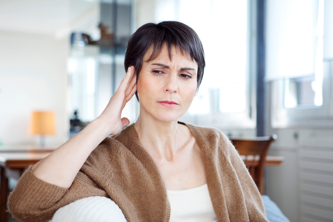 Woman holding her temple looking uncomfortable due to ear pain